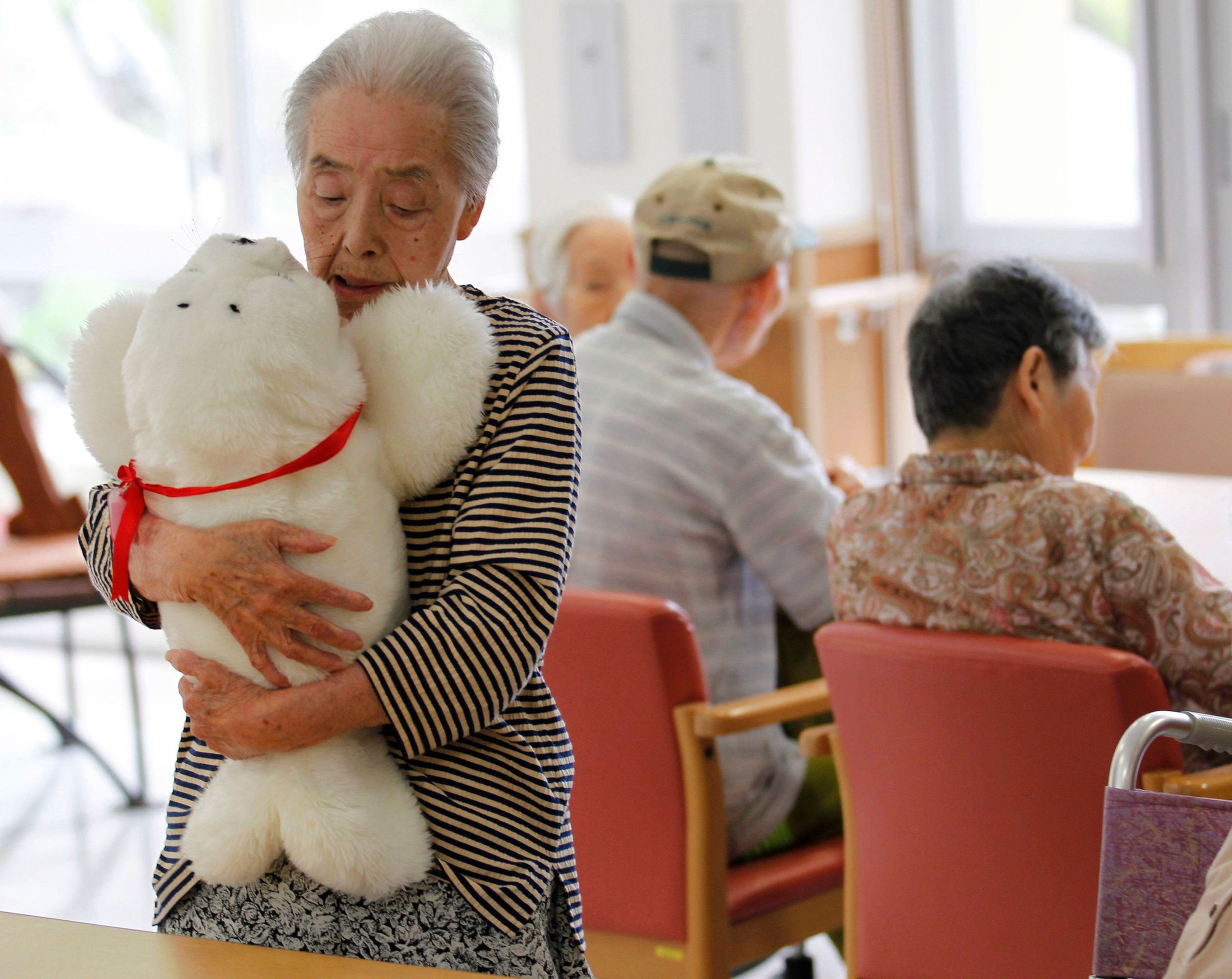 Satsuko Yatsuzaka (84) یک ربات درمانی به نام Paro را در خانه سالمندان Suisyoen نگه می دارد.